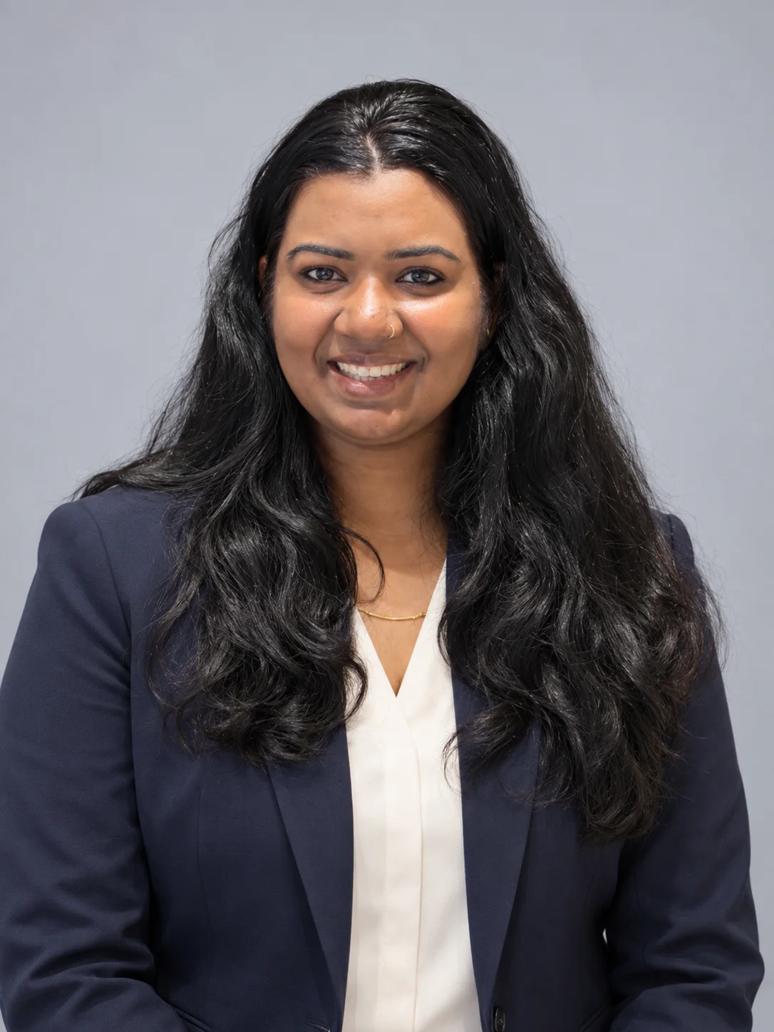 Portrait of Haritha Devadas, smiling, in a navy blazer